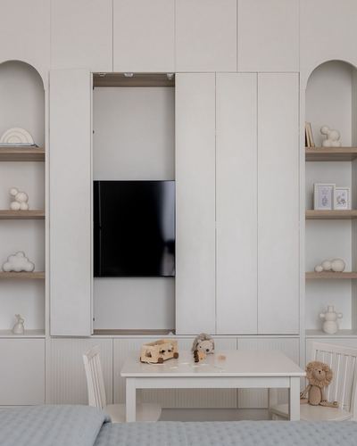 Toddler bedroom with built-in wardrobe hiding a tv, arched shelving, and a small play table