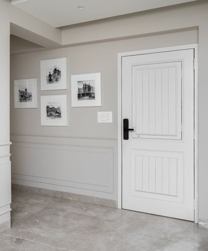Foyer with white panelled door, wainscoted grey wall, and framed architectural sketches on stone floor