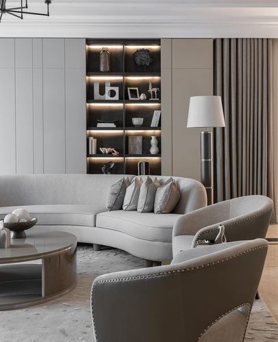 Greige living room with curved sofa, nailhead armchairs, and lit display shelving
