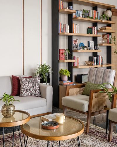 Living room corner with cane armchair, layered bookshelf, and nested round coffee tables