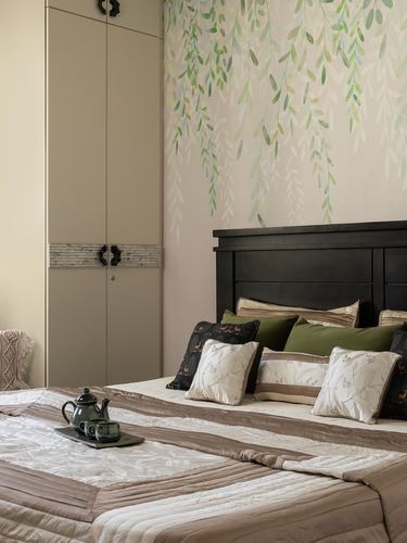 Bedroom with dark wood headboard, patterned cushions, and green leaf mural wallpaper above bed