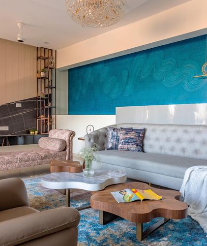 Living room with teal swirl-textured wall, grey tufted sofa, and organic wood coffee tables