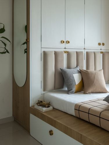 Bedroom corner with fluted wardrobes, tufted beige headboard, and oval wooden mirror