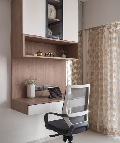 Wall-mounted wooden study desk with mesh office chair and patterned curtain beside it