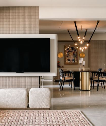 Living room with floating TV unit, boucle ottomans, and dining area with sculptural chandelier beyond