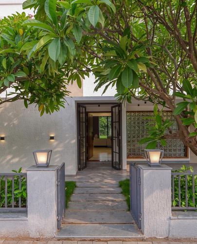 House entrance seen through tree canopy with stone path and open black door