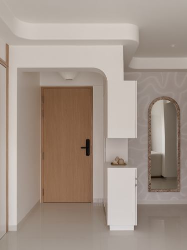 Entry foyer with curved white plaster archway, wooden door, and arched mirror on textured wall.