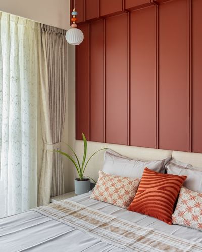 Bedroom corner with terracotta fluted paneled wall, pendant light, and patterned cushions on a bed