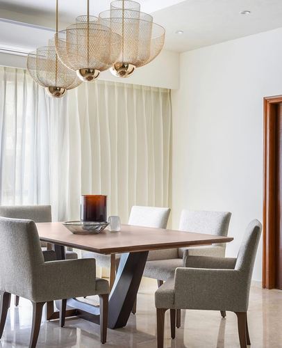 Dining room with wooden table, grey upholstered chairs, and cluster brass pendant lights above