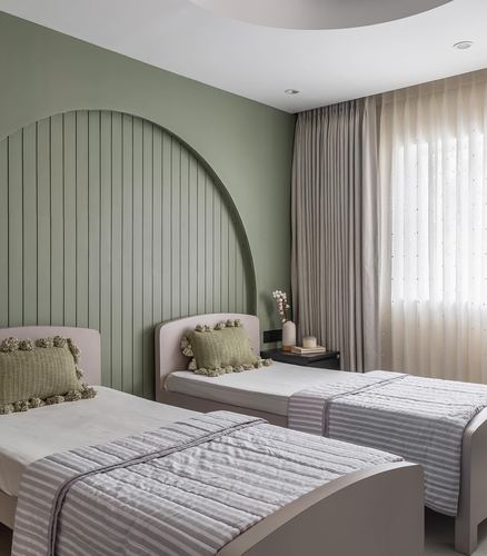 Twin beds against a green fluted arch wall in a soft-toned bedroom