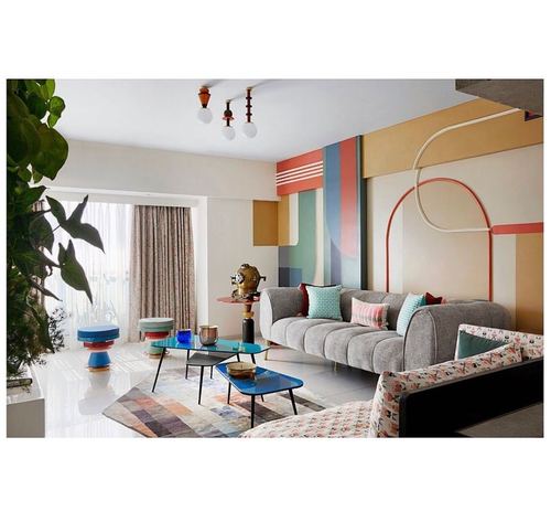 Eclectic living room with grey tufted sofa, colorful geometric mural, and blue nesting tables