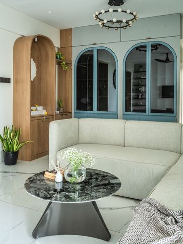 Living room with curved beige sofa, arched blue glass cabinets, and round marble coffee table