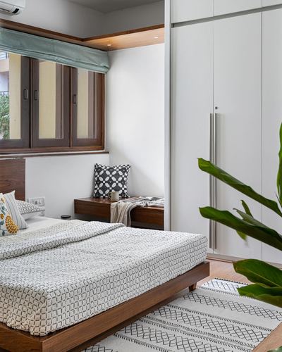 Bedroom with wooden platform bed, window seat nook, and white wardrobe wall