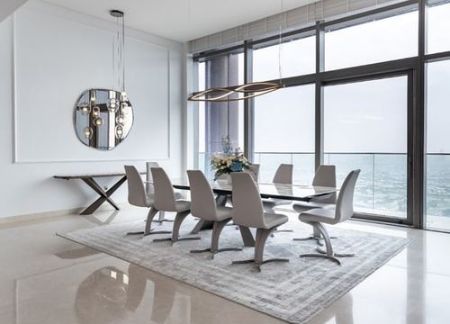 Dining room with glass table, sculptural grey chairs, floor-to-ceiling windows overlooking Dubai skyline