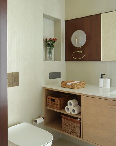 Bathroom vanity with wicker baskets, wood cabinetry, and a wall niche holding fresh flowers