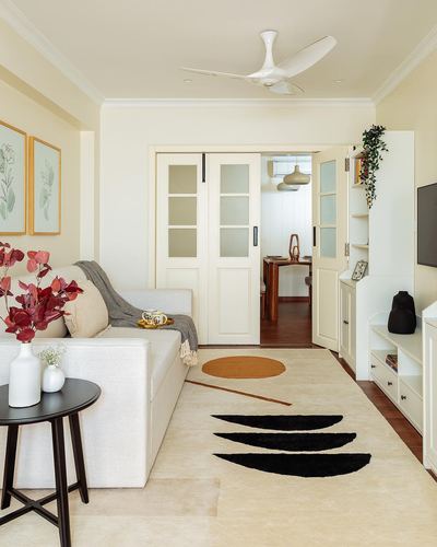 Cream living room with sofa, patterned rug, and glazed sliding doors opening to dining area