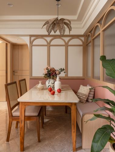 Dining nook with marble table, cane chairs, arched wood panels and pink bench seating
