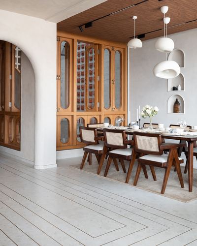 Dining room with cane chairs, wooden table, glass cabinets and sculptural pendant lights