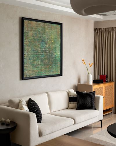 Cream sofa with black cushions beneath framed abstract art on textured plaster wall