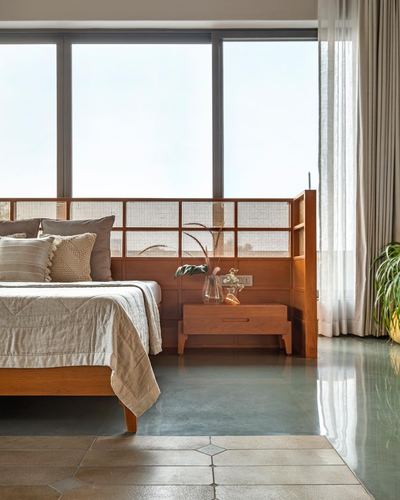 Bedroom with wooden cane-panel headboard, floor-to-ceiling windows, and dual-tone stone flooring