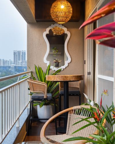Styled balcony with rattan pendant lights, scalloped mirror, live-edge table and cane stools overlooking city skyline