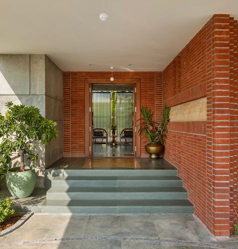 Entrance porch with exposed brick walls, stone steps, potted plants and glimpse of interior seating
