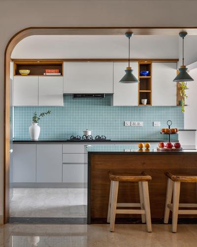 Kitchen with blue tile backsplash, white cabinets, wood arch, and two wooden stools at island