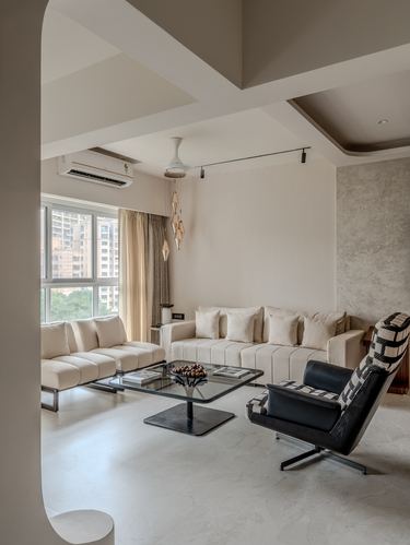 Beige living room with boucle sofas, black leather swivel chair, glass coffee table and city view