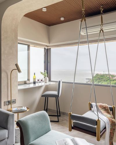 Living room corner with hanging swing chair, bar counter and sea view through large windows