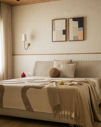 Beige upholstered bed with textured throw beneath framed abstract diptych and wall sconce