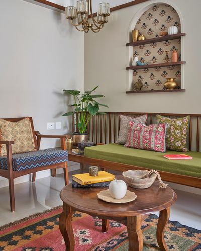 Living room corner with wooden bench, cane chair, and arched display niche with brass objects