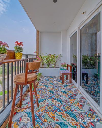 Balcony with colorful patterned tile floor, wooden bar stool, and potted plants overlooking a lake view