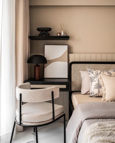 Bedroom corner with cane headboard, black cane nightstand, boucle chair and floating shelf