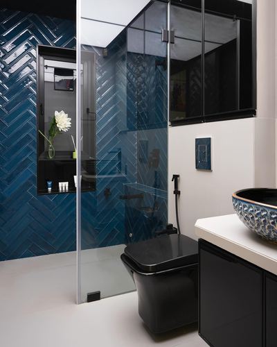 Bathroom with chevron blue tile shower, glass partition, black toilet and patterned vessel sink