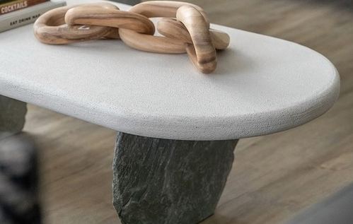 close-up of oval table with wooden chain sculpture atop a rough stone base