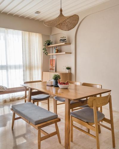 Wooden dining table with bench and chairs beneath a woven pendant light in a sunlit japandi dining room