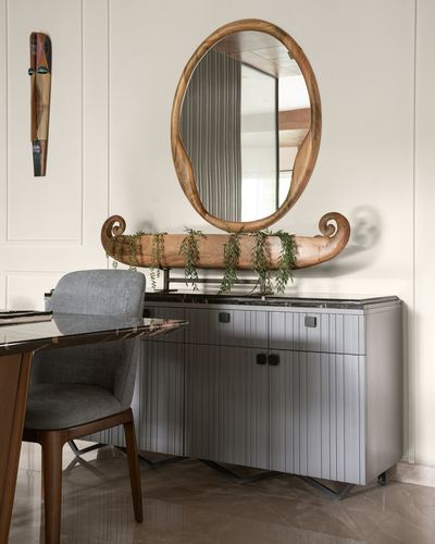 Oval wood-framed mirror above a fluted grey sideboard with a wooden boat planter and trailing greenery