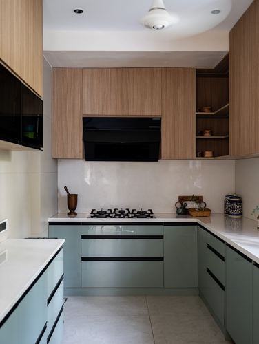 L-shaped kitchen with wood-veneer upper cabinets, sage-green lower cabinets, and white stone countertop