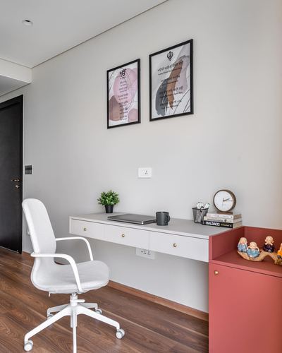 White floating desk with office chair, framed art above, red cabinet beside on wood flooring