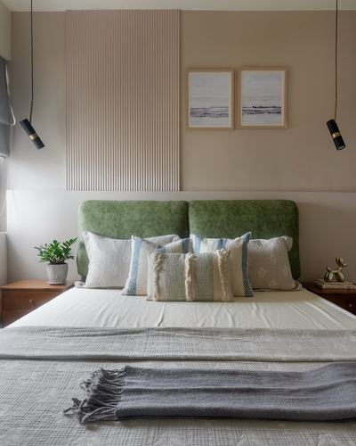 Bed with green velvet headboard against fluted panel wall, two pendant lights and framed art