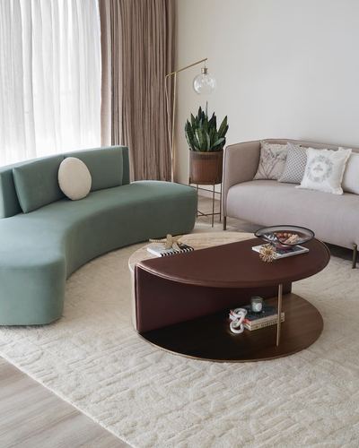 Living room with curved sage sofa, blush sofa, and oval two-tier coffee table on cream rug