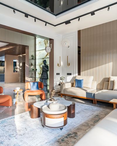 Luxury living room with fluted panelling, orange leather chairs, and layered coffee tables under natural light