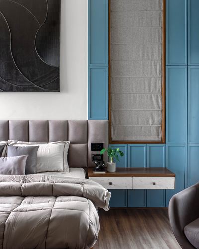 Bedroom with grey tufted headboard, blue panelled wall, and marble-fronted floating nightstand