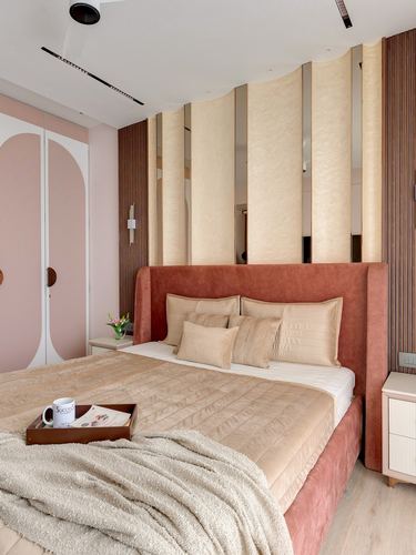 Bedroom with terracotta velvet bed against a wavy cream fluted panel wall and pink arched wardrobe