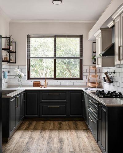 U-shaped kitchen with black cabinetry, white subway tile, and wood-look flooring, large window over sink