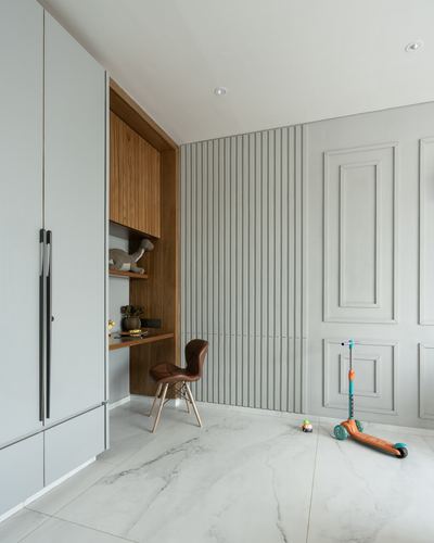 Fluted panelled wall beside a wood-clad study nook with leather chair and marble-look floor, scooter nearby