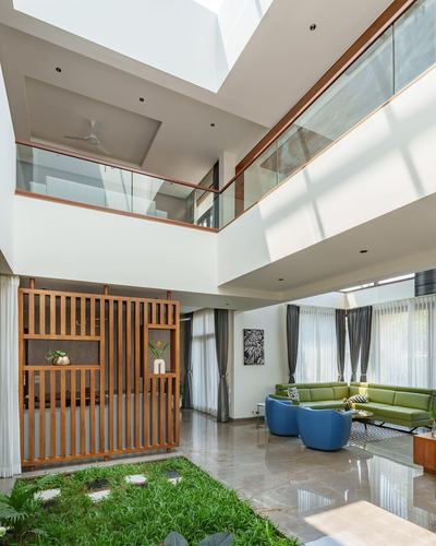 Double-height living room with wooden slatted screen, green sofa, and sunken indoor garden strip