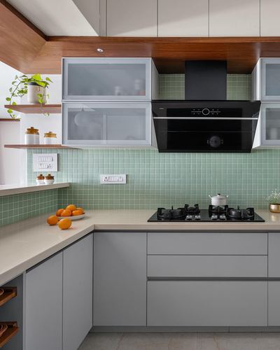 L-shaped modern kitchen with mint tile backsplash, grey cabinetry, and black chimney hood