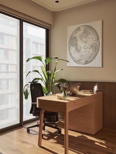 Wood-panelled home study corner with desk, laptop, plant, and round moon artwork by window