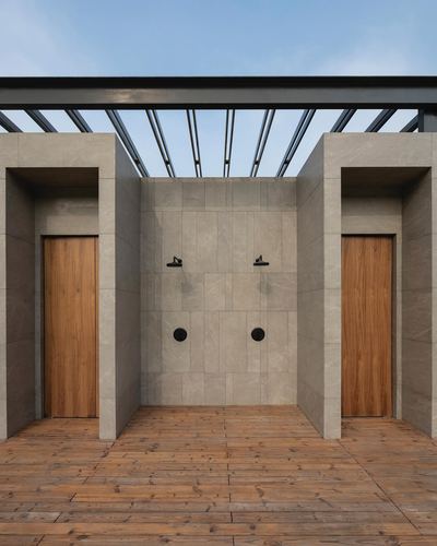 Outdoor shower area with stone walls, two teak doors, and steel pergola overhead against sky.